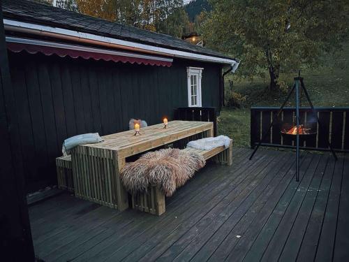 a wooden table with a bench on a deck at Gårdssmie på sjarmerende og historisk tun 