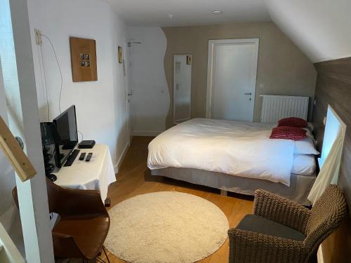 a bedroom with a bed and a desk with a television at Horenbecca Bistro & Wellness in Horebeke