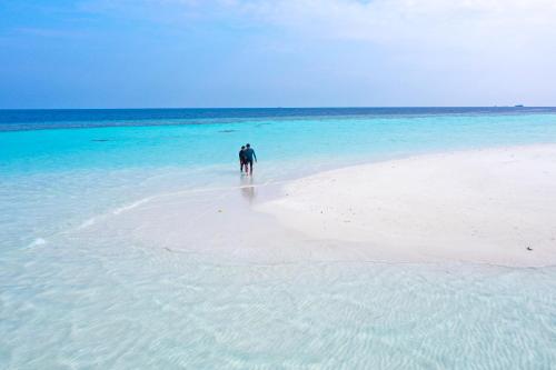 a person walking on a beach in the ocean at Manta Sea View Himandhoo in Himandhoo 