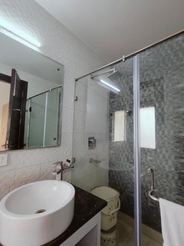 a bathroom with a sink and a glass shower at Gazebo Inn & Suites Medanta in Gurgaon