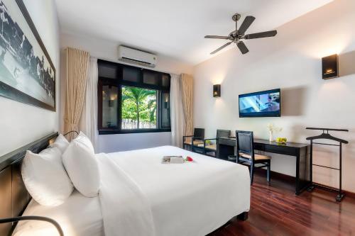 a bedroom with a white bed and a desk at HOI AN HISTORIC HOTEL in Hoi An