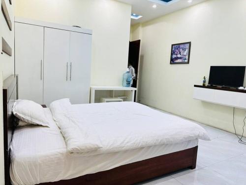 a white bedroom with a bed and a flat screen tv at Alo Home in Hòa Ðình