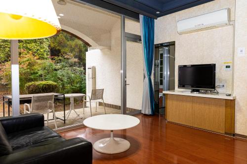 uma sala de estar com um sofá e uma televisão em Higashi Kumamoto Business Center em Ozu