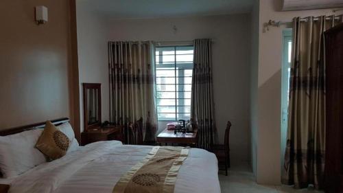 a bedroom with a bed and a table and a window at Love Hotel Hà Đông HN - by BAY LUXURY in Hà Ðông