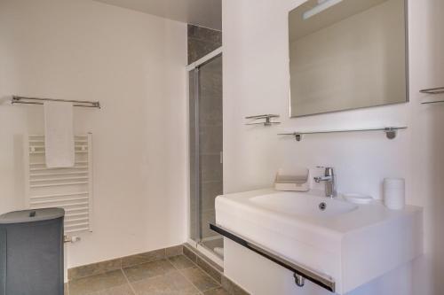 une salle de bain blanche avec un lavabo et un miroir dans l'établissement Le Sainte Cath - Au cœur de Bordeaux, à Bordeaux