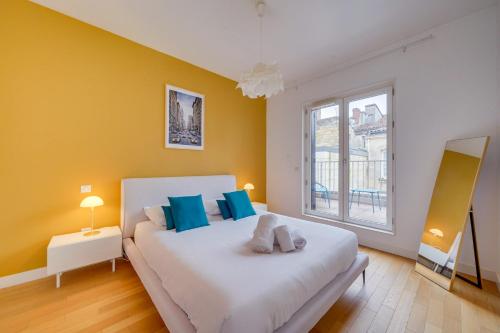 une chambre avec un grand lit blanc avec des oreillers bleus dans l'établissement Le Sainte Cath - Au cœur de Bordeaux, à Bordeaux