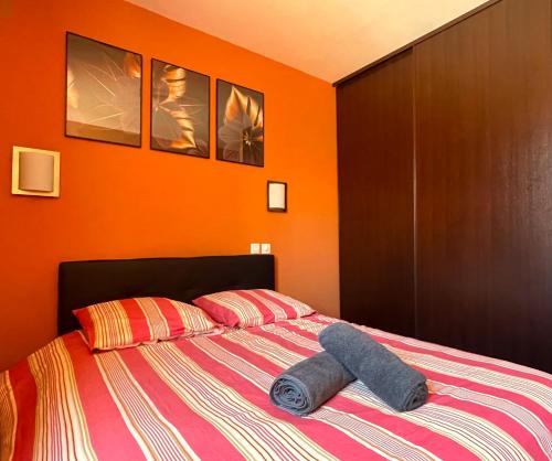 une chambre avec un lit avec un mur orange dans l'établissement L'instant Moderne Centre-ville Parking Gratuit, à Béziers