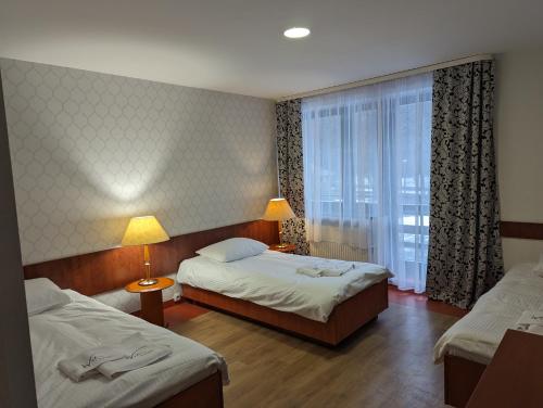 a hotel room with two beds and a window at Ośrodek Wypoczynkowy Watra in Korbielów