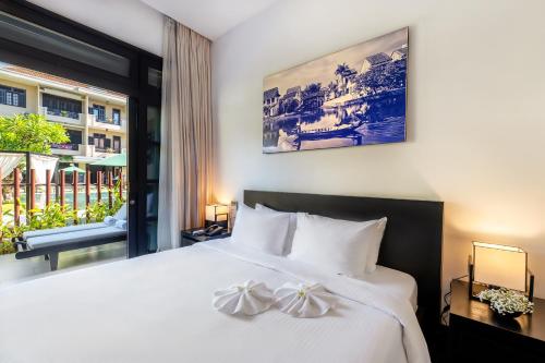 a bedroom with a large white bed with a window at HOI AN HISTORIC HOTEL in Hoi An