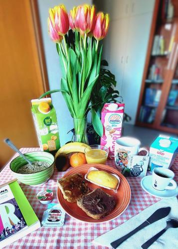 un tavolo con un piatto di cibo e un vaso di fiori di Bologna Homestay a Bologna