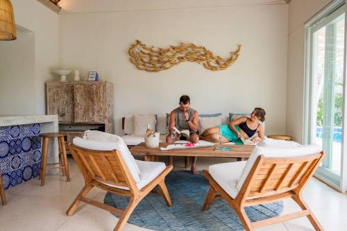 two people sitting on a couch in a living room at Villa Sari Nusa Lembongan - Three bedroom Villa in Nusa Lembongan
