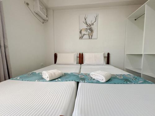 two twin beds in a bedroom with a picture of a deer at Gplace Hotel in Cebu City