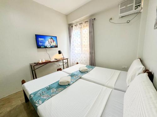 two beds in a room with a tv at Gplace Hotel in Cebu City