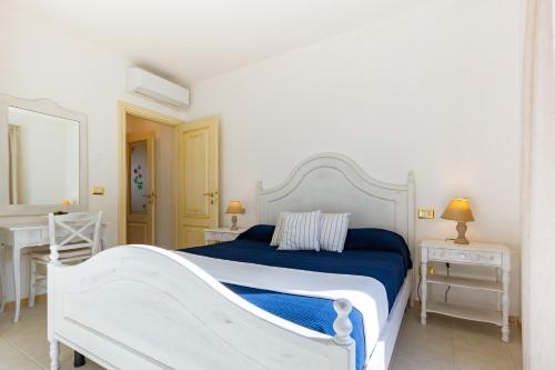 uma cama branca num quarto branco com duas mesas em Appartamento Borgo Mari PT5 - MyHo Casa em Santa Teresa Gallura
