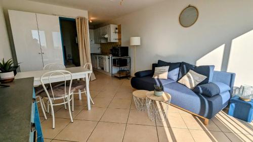 un salon avec un canapé bleu et une table dans l'établissement 050 Plein sud - Bel appartement rez de chaussée avec pk et wifi, au Cap d'Agde