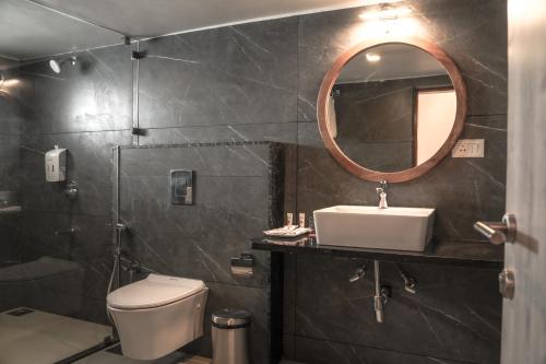 a bathroom with a toilet and a sink and a mirror at Ariena by Spree Hotels Goa in Morjim