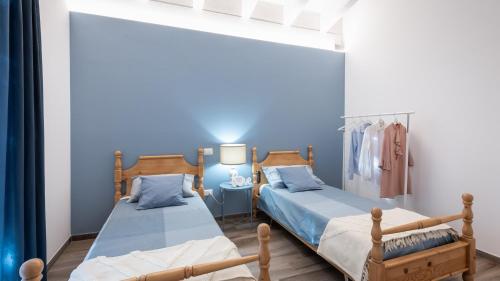 two beds in a bedroom with blue walls at DIMORA CAMPO DELLE MURA 4&2, Emma Villas in Acquaviva Picena