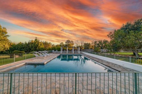 a swimming pool with a cloudy sky above it at Trulli Li Cridd in Ceglie Messapica