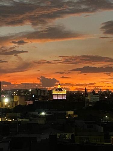 a lit up building in a city at sunset at Centro histórico Downtown Depto completo alberca climatizada AC parking free seguridad 24 hras in Guadalajara