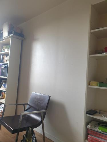 une chaise assise dans une pièce avec un mur dans l'établissement Chambre ensoleillee, à Aubervilliers
