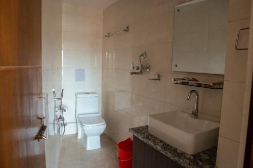 La salle de bains est pourvue de toilettes blanches et d'un lavabo. dans l'établissement Kusum Airport Hotel, à Katmandou