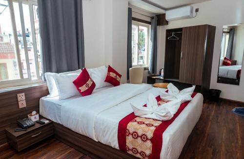 a bedroom with a large bed with red and white pillows at Kusum Airport Hotel in Kathmandu