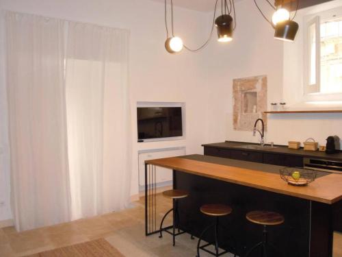 a kitchen with a counter with stools and a sink at Luxury Apartment in Historic Ortigia, Syracuse in Siracusa