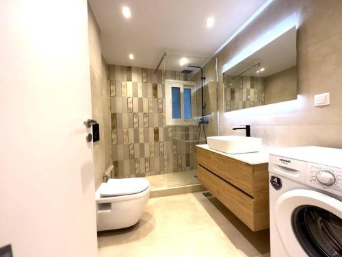 bagno con servizi igienici, lavandino e lavatrice di 2-Bed Gem in Serene Locale ad Atene