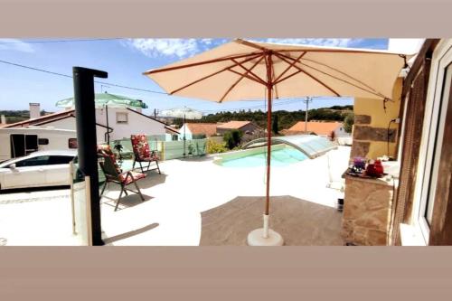 a patio with an umbrella and a pool at Nazaré WSL Experience 2025 in Carrascal