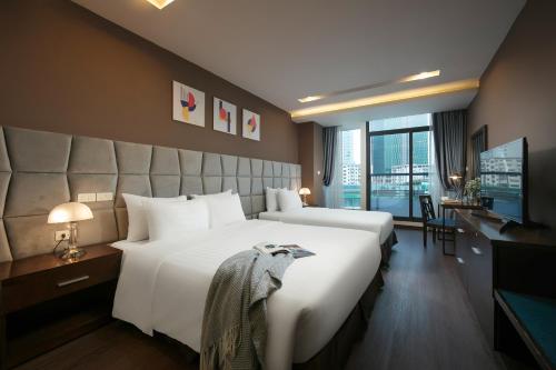 a hotel room with two beds and a television at Brilliant Me Tri Hotel & Spa in Hanoi