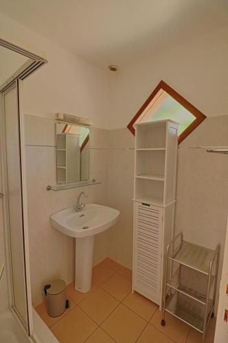 une salle de bain avec un lavabo et un miroir dans l'établissement Appartement n5 rez de jardin La Liscia, à Calcatoggio