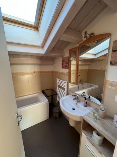 uma casa de banho com um lavatório, uma banheira e um espelho. em La Darsena apartment em Peschiera del Garda