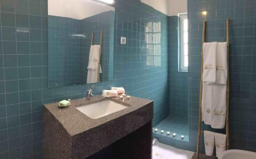 a blue tiled bathroom with a sink and a shower at Casa das Xaras in Sintra