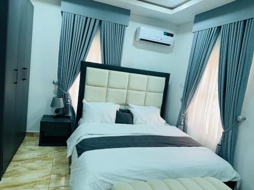 um quarto com uma cama grande com paredes e janelas azuis em Harlem apartment em Abuja