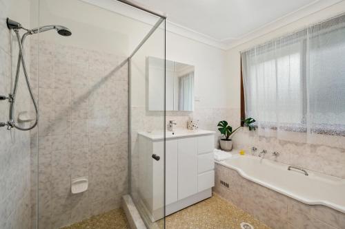 y baño con bañera, lavamanos y ducha. en Azalea Cottage, Leura NSW Australia, en Leura