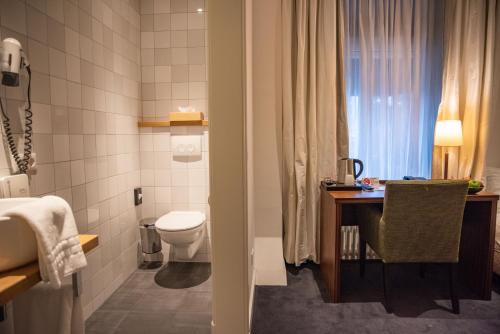 a bathroom with a toilet and a table and a sink at De Zwaan Delden in Delden