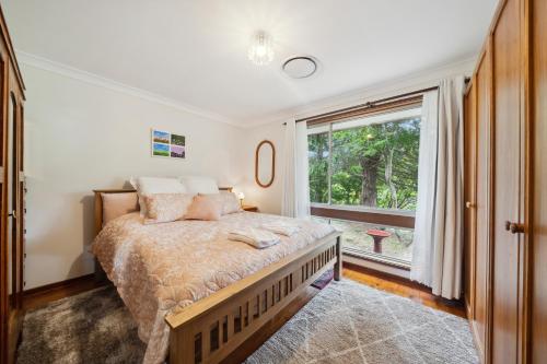 a bedroom with a bed and a large window at Azalea Cottage, Leura NSW Australia in Leura