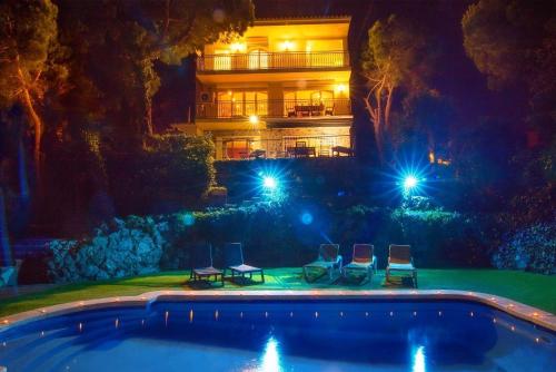 una vista notturna di una casa con piscina di Villa con piscina privada climatizada 29ºC a Santa Susanna