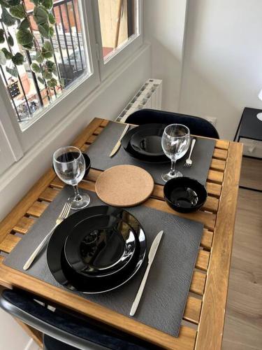 une table en bois avec des assiettes et des verres à vin dessus dans l'établissement Studio cozy proche Paris, à Gentilly