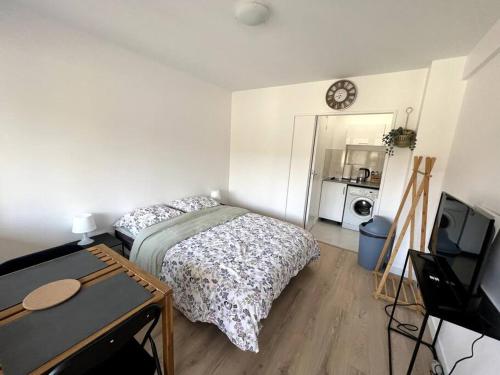 a bedroom with a bed and a table and a tv at Studio cozy proche Paris in Gentilly