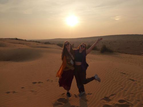 Due ragazze che camminano nel deserto al tramonto di Martine guest house a Jaisalmer