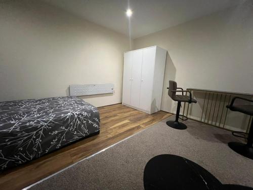 a bedroom with a bed and a cabinet and a chair at Modern Studio in Rayners Lane Pinner Harrow near wembley Greater London in Pinner