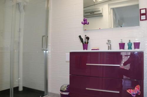 La salle de bains est pourvue d'une commode violette et d'un miroir. dans l'établissement Appart 108, Port Soleil au village naturiste, au Cap d'Agde