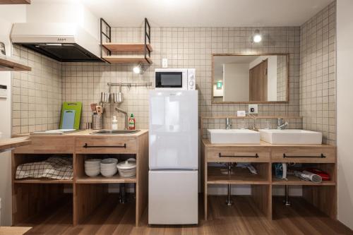 La cuisine est équipée d'un réfrigérateur blanc et de 2 lavabos. dans l'établissement Pangoo Ebisu 恵比寿【渋谷3分，六本木3分】惠比寿駅徒步8分, à Tokyo