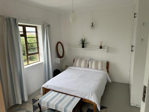a white bedroom with a bed and a window at Lighthouse Villa in Cape St Francis
