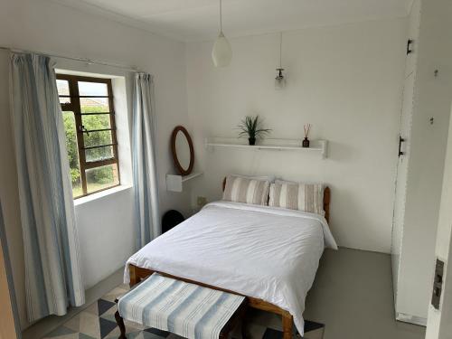 a white bedroom with a bed and a window at Lighthouse Villa in Cape St Francis