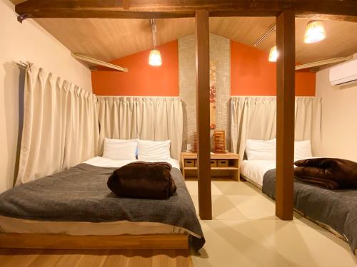 two beds in a room with orange walls at Pangoo Ebisu 恵比寿【渋谷3分，六本木3分】惠比寿駅徒步8分 in Tokyo