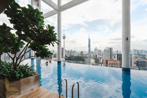 een zwembad op het dak van een gebouw met een skyline van de stad bij Colony Chow Kit Guesthouse in Kuala Lumpur