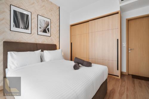 een slaapkamer met een groot wit bed en een houten deur bij Colony Chow Kit Guesthouse in Kuala Lumpur