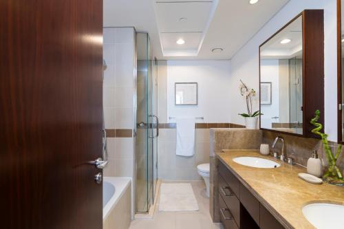 a bathroom with two sinks and a shower and a toilet at Prestige Living 2BR with Full Burj Khalifa and Fountain View by Auberge in Dubai